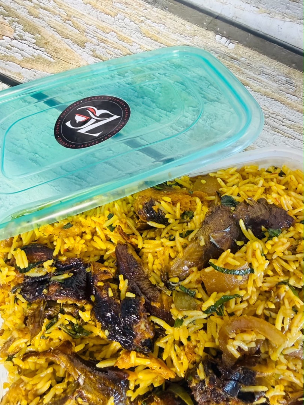 Native rice with smoked fish and scent leaves in a Zoaney container