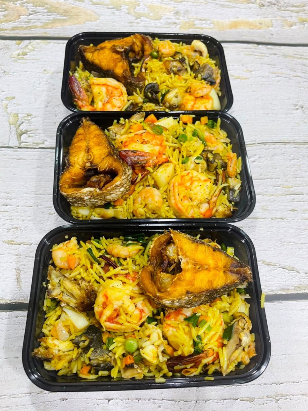 Seafood pineapple fried rice with prawns and fried fish packed in delivery trays