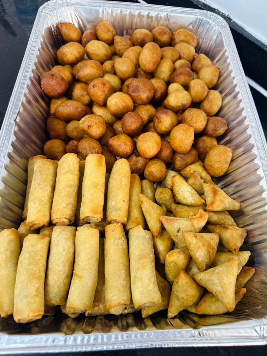 Tray of puff-puff, spring rolls and samosas